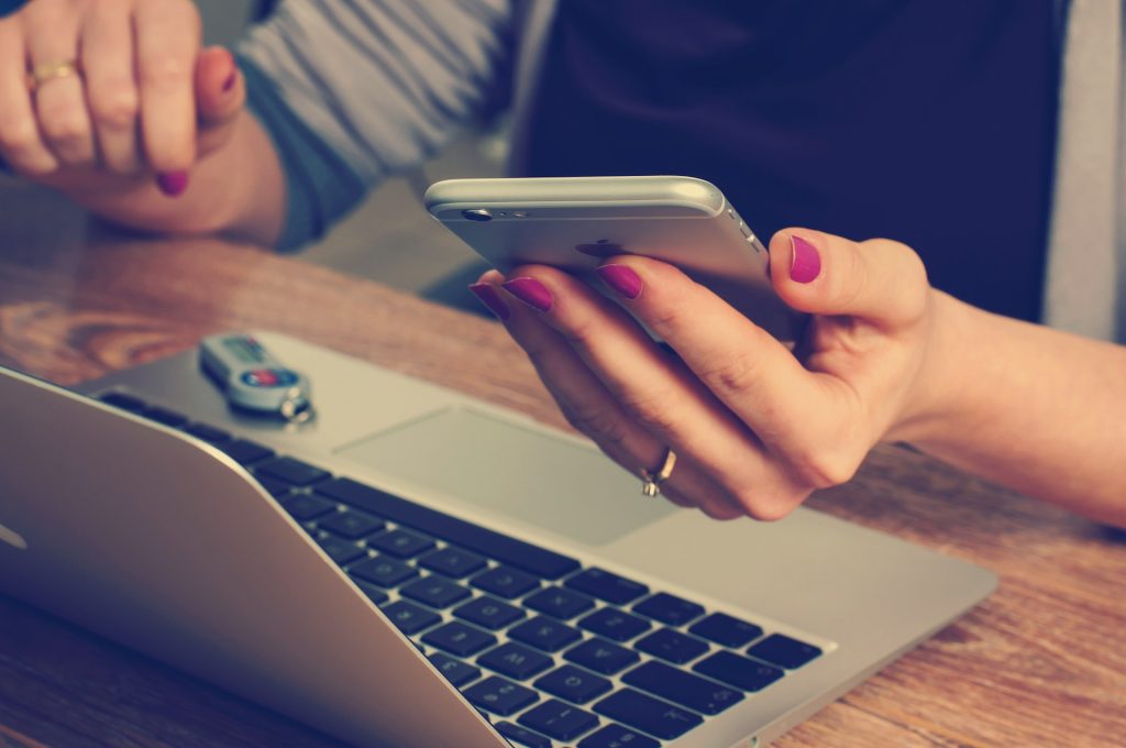 Woman looking at phone and laptop